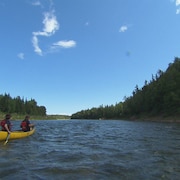 Deux hommes descendent la rivière Bonaventure à bord d'une embarcation louée par l'entreprise Cime Aventures.