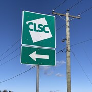 La pancarte du CLSC plantée près d'une route indique la direction à prendre pour s'y rendre.