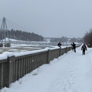 Une promenade enneigée le long d'une rivière gelée.