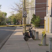 Un VUS et un vélo électrique devant un ruban jaune installé par la police. 