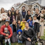 Dix adultes, neuf enfants et un chien devant une résidence.