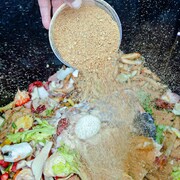 La main du chef cuisinier, Stephane Baloy, en train de mettre un mélange de son de blé et de micro-organismes sur des déchets organiques  le 11 juin 2012.  