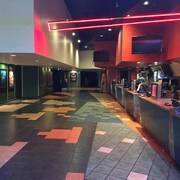 Comptoir de restauration du cinéma 9, avec plancher carrelé, entrée des salles de cinéma et néon au plafond.
