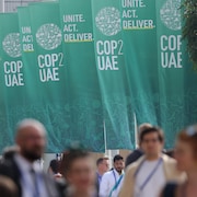 Des délégués marchent devant des banderoles de la COP28. 
