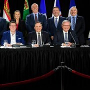 Les 13 premiers ministres des provinces et territoires canadiens sourient à la caméra, placés en deux rangées.