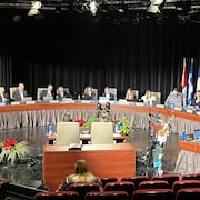 Les membres du conseil municipal, du bureau du greffe et le directeur général de la Ville de Gatineau sont assis à leurs sièges respectifs dans la salle de réunion du conseil à la Maison du citoyen.