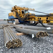 Un véhicule de construction et des tiges de métal allongées sur le sol.