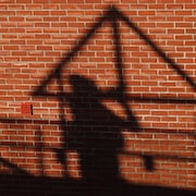 L'ombre d'un travailleur de la construction apparaît sur un mur de briques rouges.