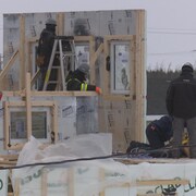 Sept personnes construisent une maison. 