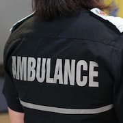Une femme porte une chemise sur laquelle se trouve un écusson portant l'inscription « Technicien ambulancier - Paramédic - Québec ».