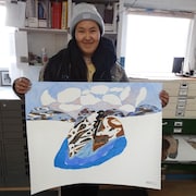 L'artiste Ooloosie Saila pose pour une photo en montrant une oeuvre, dans le studio de Kinngait, à Kinngait au Nunavut, en 2017. 