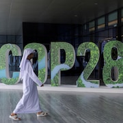 Une personne passe devant un panneau « COP 28 » lors du Changemaker Majlis, un atelier de réflexion d'une journée destiné aux dirigeants d'entreprises et axé sur l'action climatique, à Abou Dhabi.