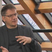 Un homme parle devant un toit vitré.