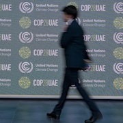 Un homme passe devant une affiche faisant la promotion de la COP28.