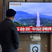 Des Coréens écoutent le reportage d'une chaîne d'information sud-coréenne portant sur un tir de missile.  