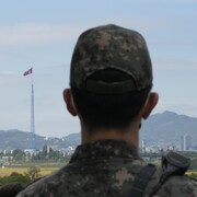 Un soldat regarde un drapeau nord-coréen flotter de l'autre côté de la frontière.