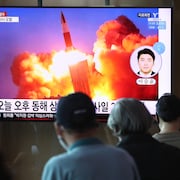 Des personnes regardent une télévision montrant une image d'un lancement de missile. 