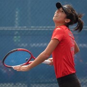 Une jeune fille en train de jouer au tennis.