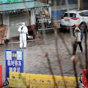 Un homme habillé d'un habit de protection contre la contamination se tient debout dans le marché fermé.