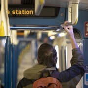 Une personne se tient dans une rame de métro.