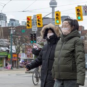 Deux femmes marchent dans le quartier chinois à Toronto en portant un masque.
