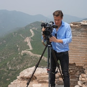 Le journaliste Yvan Côté manipulant une caméra au sommet de la muraille de Chine.
