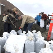 Des citoyens remplissent des sacs de sable en prévision des inondations.