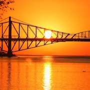 Vue sur le pont de Québec avec en arrière-plan, un soleil couchant.