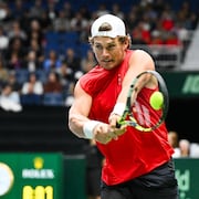 Un homme frappe une balle de tennis dans un amphith&eacute;&acirc;tre.