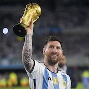Lionel Messi tient le trophée de la Coupe du monde de soccer.