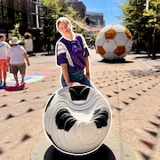 La journaliste Victoria Kopiloff en train de poser avec une statue de ballon de soccer.