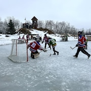 Des joueurs de hockey en bottine s'affrontent sur la patinoire. 