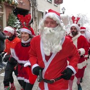 Des personnes déguisées en père Noël en train de courir dans les rues du Vieux-Québec.