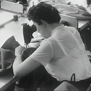 Une couturière courbée sur sa machine à coudre dans une manufacture.