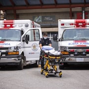 Un ambulancier pousse une civière entre deux ambulances à l'hôpital St-Paul de Vancouver.  