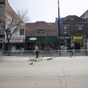 Un homme à vélo dans une rue commerciale presque déserte.