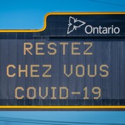Un panneau au-dessus de l'autoroute portant le message : restez chez vous, COVID-19.