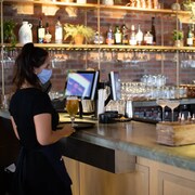 Deux serveurs portent un masque dans le bar où ils travaillent.