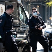 Deux policiers de Vancouver au centre-ville. L'un d'eux porte un masque. 