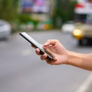 Une personne tient dans sa main droite un téléphone.