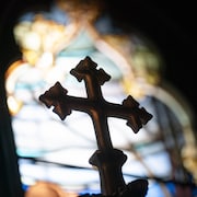 Photo d'une croix avec un vitrail en arrière-fond.