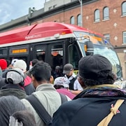 Des passagers tentent de monter à bord d'un autobus à l'intersection de Broadview et Danforth pendant que l'interruption du service de métro.