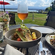 Des mets et un verre de rosé sur une table extérieure avec vue sur la mer de Salish.