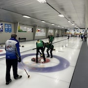 Des joueurs de curling sur une glace pendant une partie.