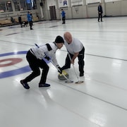 deux hommes jouent au curling
