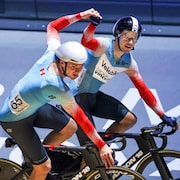 Sur leur vélo, Dylan Bibic et Mathias Guillemette se tiennent la main en signe de victoire. 