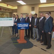 La première ministre Danielle Smith derrière un podium entourée de candidats.