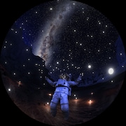 Un homme en tenue d'astronaute se tient devant un ciel étoilé où l'on peut apercevoir une galaxie au loin. 