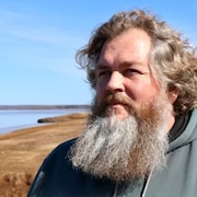 Un homme barbu se tient debout près de la rivière Avon.