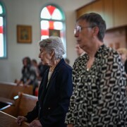 Des femmes âgées sont debout dans une église.